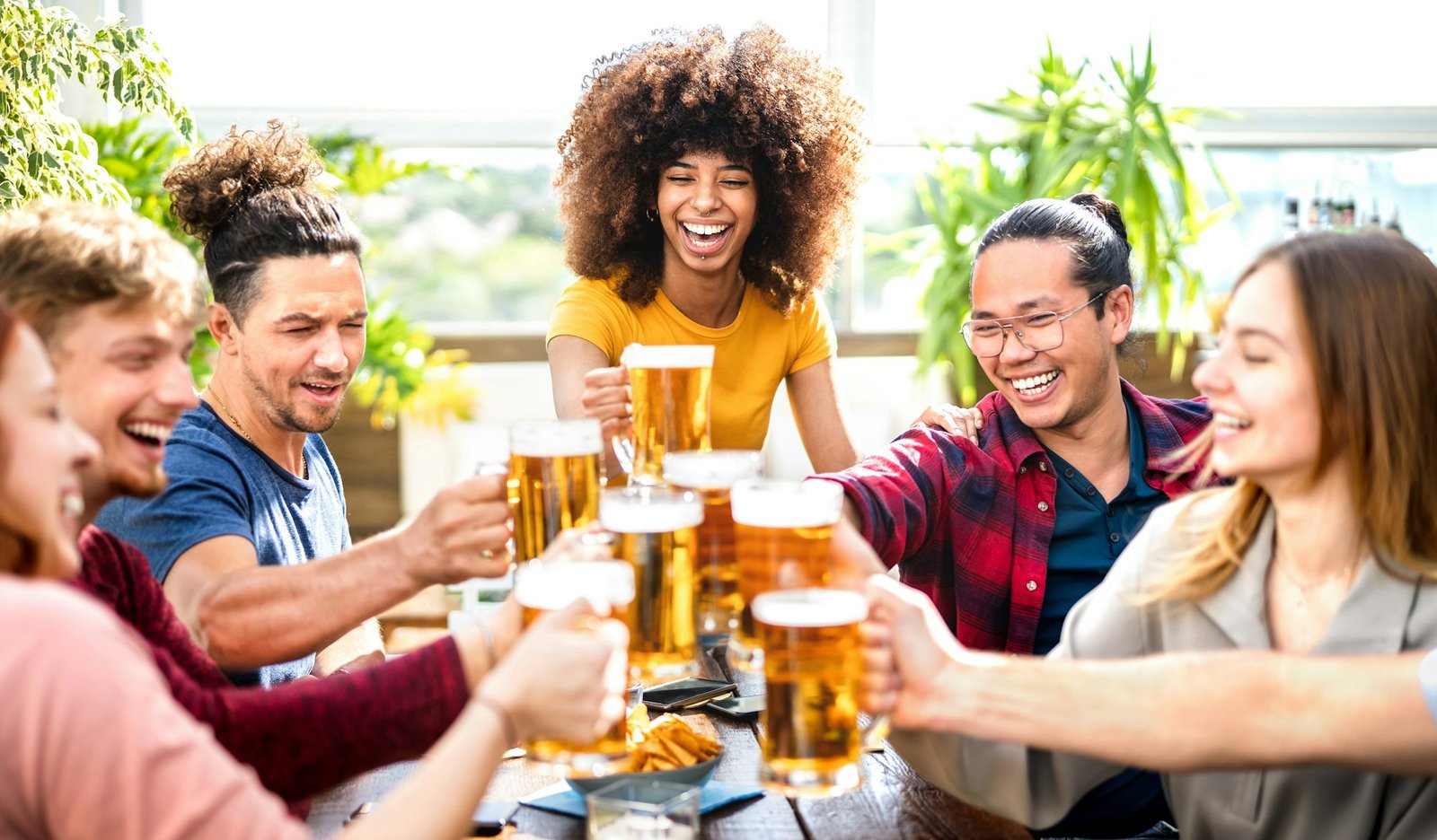 Young trendy people drinking and toasting beer at brewery bar restaurant